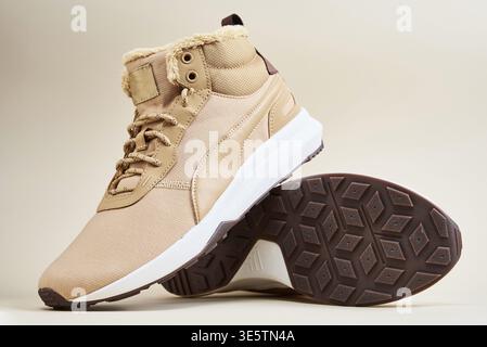 Stivali maschi su sfondo beige. Paio di scarpe invernali eleganti in pelle Foto Stock