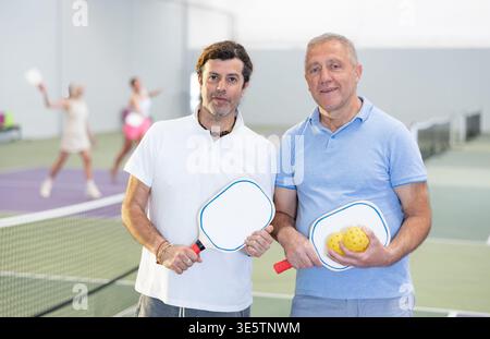 Due giocatori maschi di pickleball in piedi sul campo interno Foto Stock