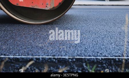 Pavimentazione a rulli di vapore nuova strada asfaltata, posa di catrame fresco per lo sviluppo delle infrastrutture Foto Stock