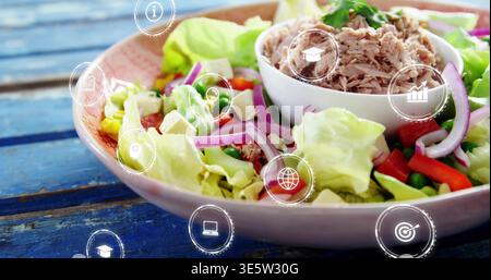 Mostra una grande ciotola in ceramica con insalata, piccolo ramekin bianco che tiene il tonno sulle icone superiori blu Foto Stock