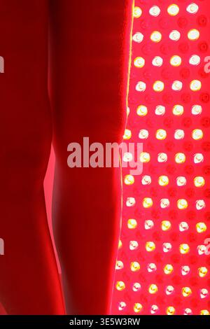 Giovane donna che riceve una terapia a luce rossa sulla parte inferiore del corpo Foto Stock