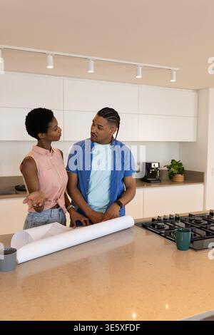 Coppia afroamericana che rivede il progetto di Kitchen Island, con due tazze e piano cottura Foto Stock