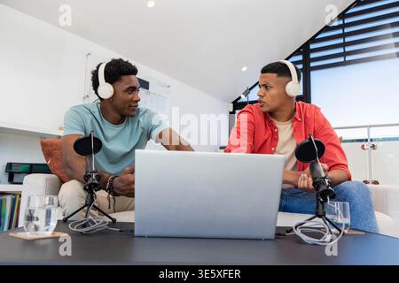 Registrazione di diversi amici maschi che si rivolgono al laptop in studio di registrazione, con microfoni Foto Stock