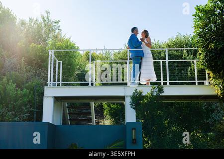 Indossate una tuta blu e un abito bianco che si affaccia l'uno di fronte all'altro su un balcone in metallo con guide per cavi Foto Stock