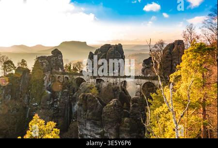 Vista panoramica all'alba del Ponte Bastei, illuminato dalla luce dorata dell'inverno, costruito su torreggianti rocce di arenaria, con il lontano Lilienstein sul... Foto Stock