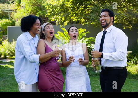 Diversi gruppi di nozze sul prato con flauti in mano, sposa con abito, sposo con bottiglia di apertura con cravatta Foto Stock