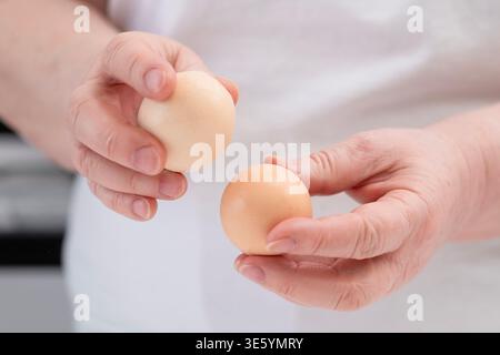 Primo piano delle mani delle donne che pelano le uova. Foto Stock