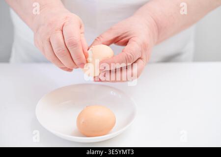 Primo piano delle mani delle donne che pelano le uova. Foto Stock