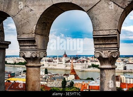 Incredibile vista sulla riva del Danubio, sul Parlamento, attraverso gli archi del Bastione dei pescatori di Budapest Foto Stock
