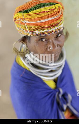 Odisha, India - 26 marzo 2026: Veduta di una donna tribale adornata da sorprendenti anelli in argento sul collo e un vibrante turbante e multicolore, il suo sguardo accattivante Foto Stock