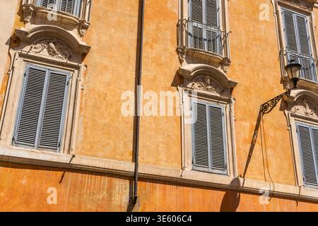 Facciata arancione della casa in via Italia Roma. Antico edificio storico nel centro della città. Persiane per finestre italiane Foto Stock