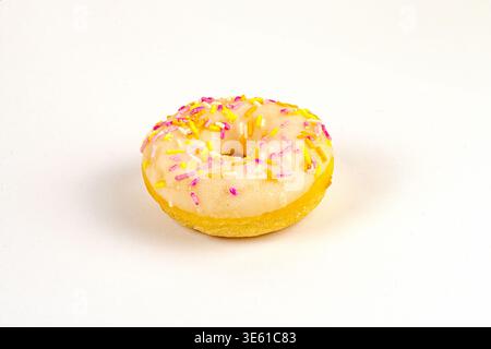 Ciambella rotonda, marrone chiaro o dorata con cospargi su carta con motivi testurizzati di colore pastello rosa, giallo, probabilmente bianco fuori centro c Foto Stock