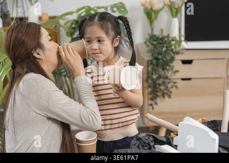 Madre e figlia selezionano i materiali riciclabili mentre si godono un momento di gioco che incoraggia una vita sostenibile e una consapevolezza ambientale Foto Stock
