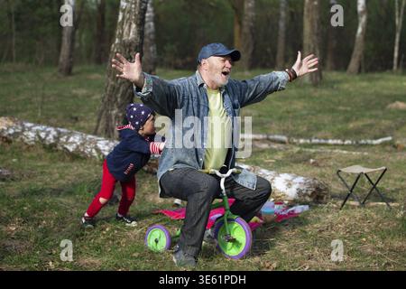Nonno e nipote si divertono a giocare con una bicicletta in natura Foto Stock