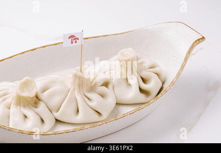 Cibo, tre gnocchi tradizionali georgiani khinkali serviti in un piatto di ceramica. Ripieno di carne succoso avvolto in un impasto morbido. Classico e autentico nazionale Foto Stock