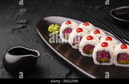 Cibo: Un piatto offre sushi panini preparati con gusto, ripieni di tonno fresco e condimenti vivaci. Un piccolo piatto di salsa e accompagnamento di wasabi Foto Stock