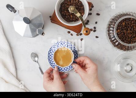 Una tazza di caffè appena fatto nelle mani di una donna. Messa a fuoco selettiva, vista dall'alto Foto Stock