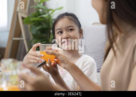 Una madre e una figlia condividono un momento di gioia su un'alimentazione sana, gustando succhi freschi e insalate, promuovendo il benessere e il legame familiare Foto Stock