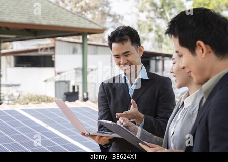 Un gruppo diversificato di professionisti che collaborano a strategie e progetti per le energie rinnovabili, sottolineando il lavoro di squadra e la sostenibilità Foto Stock