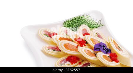 Cibo, coloratissimi sushi roll sono ben esposti su un piatto. Gli involtini presentano strati di pesce, riso e guarnigioni, completati da un condimento luminoso Foto Stock