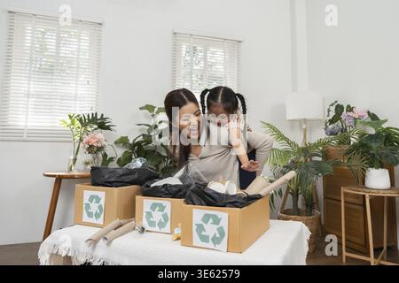 Un momento di gioia come madre guida sua figlia attraverso il processo di smistamento dei materiali riciclabili a casa. Questa immagine evidenzia il collegamento familiare e il sustai Foto Stock