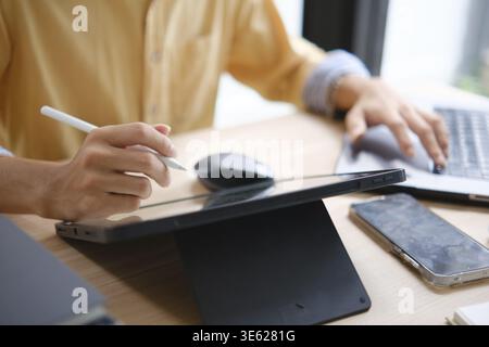 Web designer maschile che disegna con un tablet grafico al tavolo in ufficio, primo piano Foto Stock