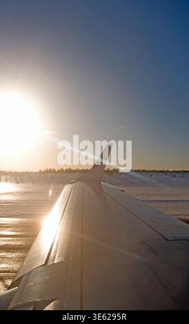 Kuusamo, Finlandia – 17.02.2019: Vista sull'ala di una livrea Embraer 190 di Finnair sulla pista di rullaggio dell'aeroporto di Kuusamo, verso il sole splendente Foto Stock