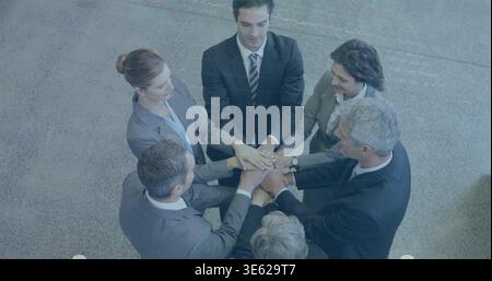 Unendo sei colleghi mettendo le mani insieme sul pavimento grigio macchiato della hall in abiti e mani impilate Foto Stock