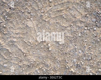 Terreno sterrato con pietre di piccole dimensioni e tracce visibili degli pneumatici in un ambiente esterno Foto Stock