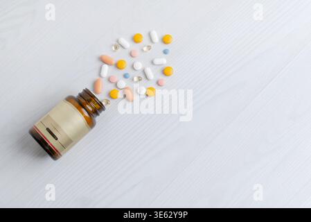 Flacone aperto con pillole assortite versate su superfici pulite, prodotti farmaceutici e assistenza sanitaria Foto Stock