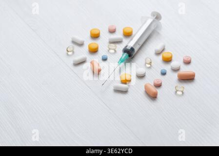 Siringa medica circondata da pillole su superficie pulita, sanità e concetto farmaceutico Foto Stock