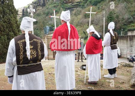 Fratelli religiosi visti da dietro a guardia di Gesù Cristo sulla croce durante i rituali del venerdì Santo, Corleone, Sicilia, Italia. Foto Stock