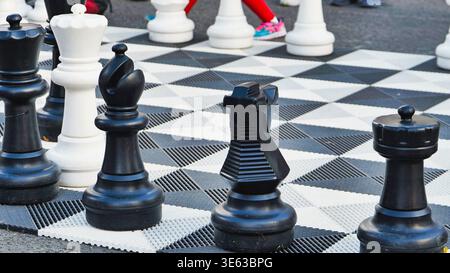 Grande set per scacchi all'aperto con pezzi in bianco e nero su una scacchiera a scacchi Foto Stock