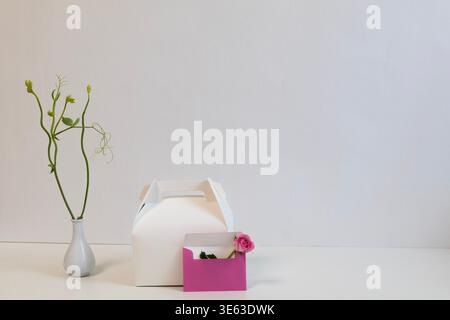 Confezione regalo minimalista con busta e fiore rosa, elegante composizione STILL Life con spazio per le copie Foto Stock