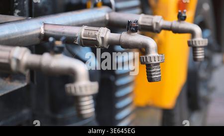 Rubinetti multipli in metallo su un tubo che fornisce acqua per l'igienizzazione o l'irrigazione Foto Stock