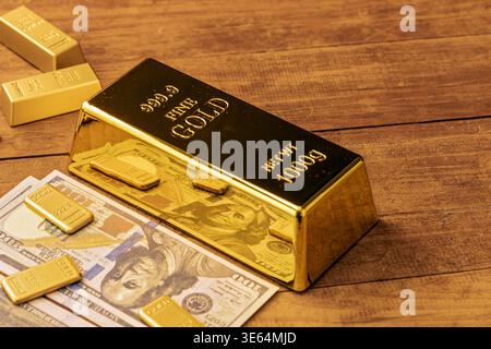 Immagine di alta qualità di scintillanti lingotti d'oro e contanti in valuta statunitense esposti su un tavolo di legno, che rappresentano il successo finanziario, l'accumulo di ricchezza, investi Foto Stock