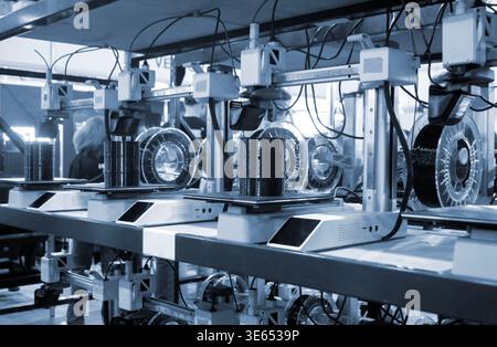 Molte stampanti 3D stampano oggetti. Stampanti 3D che creano forme da plastica fusa che fuoriesce dall'estrusore. Primo piano della stampante 3D. Utilizzo della stampante 3D in un oggetto di stampa di processo da plastica nera fusa Foto Stock