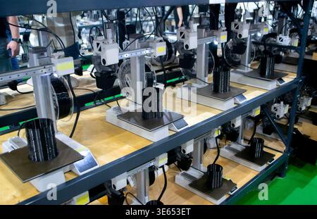 Molte stampanti 3D stampano oggetti. Stampanti 3D che creano forme da plastica fusa che fuoriesce dall'estrusore. Primo piano della stampante 3D. Utilizzo della stampante 3D in un oggetto di stampa di processo da plastica nera fusa Foto Stock