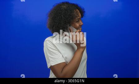 Donna sorridente e che tiene lo smartphone all'orecchio in studio; ottimismo di conversazione positivo. Foto Stock