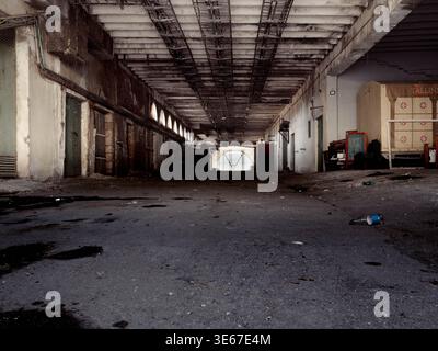 Interno abbandonato dell'edificio del mercato municipale di Tallinn con detriti e bancarelle vuote, Estonia, marzo 2026 Foto Stock