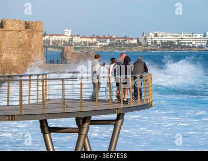 La gente guarda le onde che si infrangono sulla costa al castello di Pafos (Paphos) (forte medievale), Cipro Foto Stock