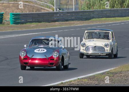 La Porsche 356 (C) SC guida la Austin Mini Cooper S. Un classico inseguimento catturato dal fronte sul rettilineo principale a Estoril Classics 2023 Foto Stock