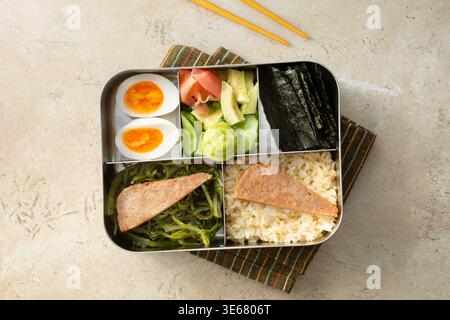Una vista dall'alto verso il basso di una scatola bento, con carne a pranzo e salsa di soia di riso. Foto Stock