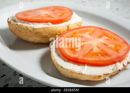 Vista di un bagel, ricoperto di formaggio spalmabile e pomodori. Foto Stock