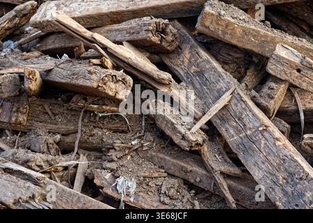 Una vista dettagliata dall'alto verso il basso di un mucchio di traverse in legno scartate, in decomposizione, mescolate con terreno e detriti industriali. Il legno mostra segni pesanti Foto Stock