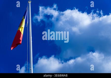 Bandiera nazionale della Repubblica di Moldavia appesa al palo contro il cielo blu con nuvole. Bandiera moldava, asta di bandiera, sfondo cielo. Foto Stock