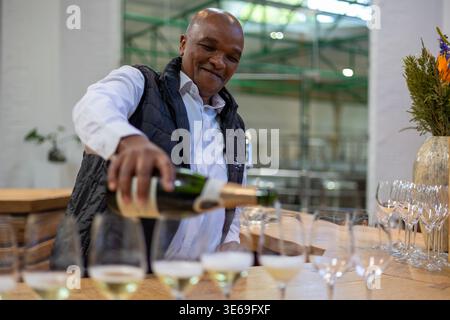 Maestro sommelier che versa vino bianco durante una degustazione alla Klein Constantia Wine Estate, Constantia, Città del Capo, Sudafrica. Foto Stock