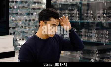 Giovane che prova nuovi occhiali nel negozio di occhiali Foto Stock