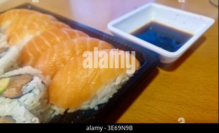Nigiri freschi di salmone e sushi in un contenitore da asporto, pronti per il consumo Foto Stock