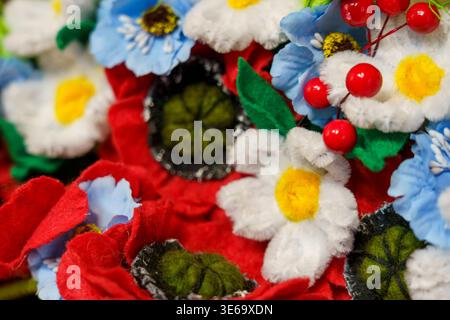 Fiori colorati realizzati in tessuto sono esposti su un tavolo in una fiera dell'artigianato Foto Stock